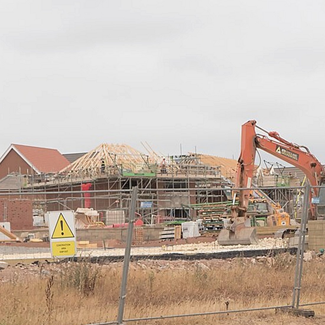 Roof timbers open on a house, with an excavator on the site